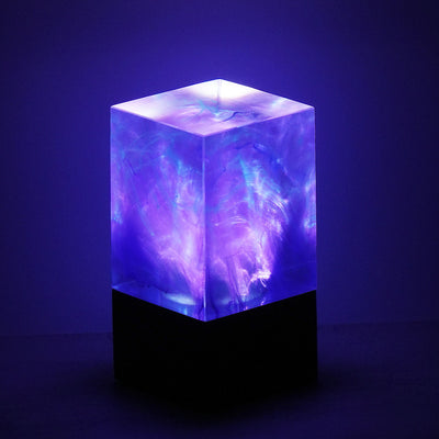 A illuminated cube-shaped night light emitting a vibrant purple light, resembling a galaxy or nebulas.