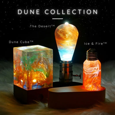A collection of artistic lamps with a desert-inspired design, featuring warm orange and yellow tones, displayed under the name 'DUNE COLLECTION'.